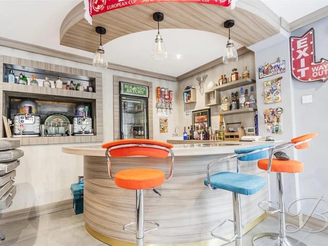 A stunning bar area with space for furniture, featuring a built-in bar and windows to the rear elevation.