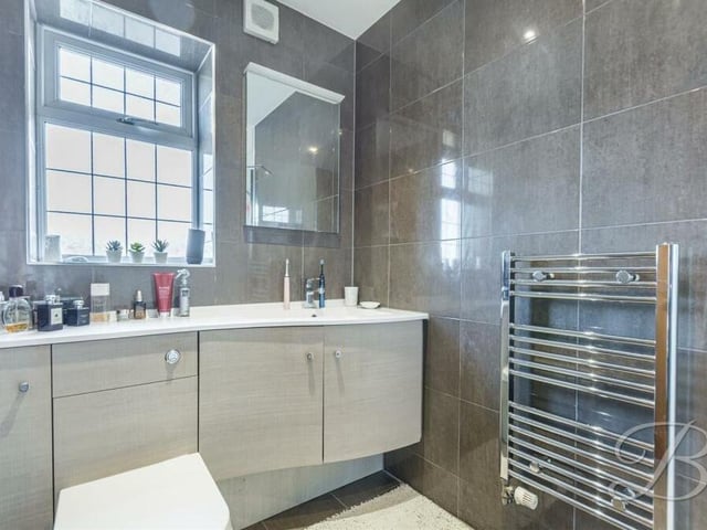 The modern en suite to the master bedroom comprises a shower cubicle with mixer shower, vanity unit with hand wash basin and WC, and a chrome, heated towel-rail.