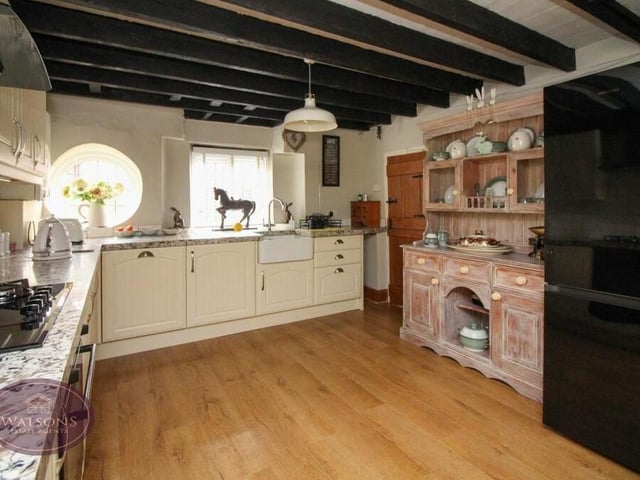 Ceiling beams and a wood-effect laminate flooring ensure the kitchen fits in nicely with the rest of the house. Quartz work surfaces incorporate an inset Belfast sink, while there is plenty of space for a fridge/freezer.