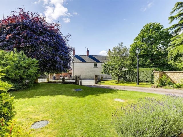 The garden offers access to both a garage and a summer house leading to several upper garden patios for relaxing and entertaining, along with a driveway spacious enough for multiple vehicles. And lit by a vintage lamppost.