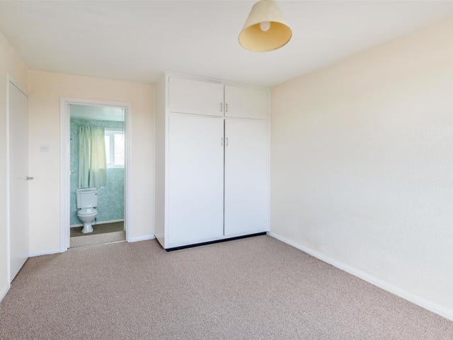 The third bedroom, facing the side of the house, boasts fitted wardrobes, with hanging rails and shelving, and storage cupboards above. It has access to en suite facilities too.