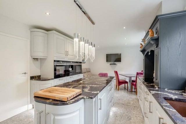 The stylish central island in the kitchen/breakfast room includes a food preparation area, further base units and drawers, granite worktops and space for stools at one end.