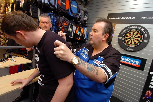 Phil The Power Taylor signs the top top of darts fan David Grove, of Sprotbrough, during his autograph session at InterSport, Doncaster in 2009