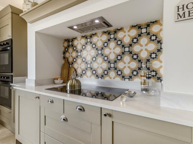 A close-up of a corner of the kitchen, showing an integrated five-ring induction hob with built-in extractor hood above.