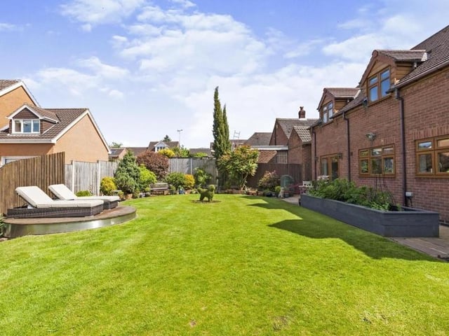 Our last two photos focus on the stunning back garden. It is wonderfully presented, complete with a pristine lawn, mature shrubs and bushes, flowerbed edging and a raised decked area, which is perfect for sunbathing in the summer.