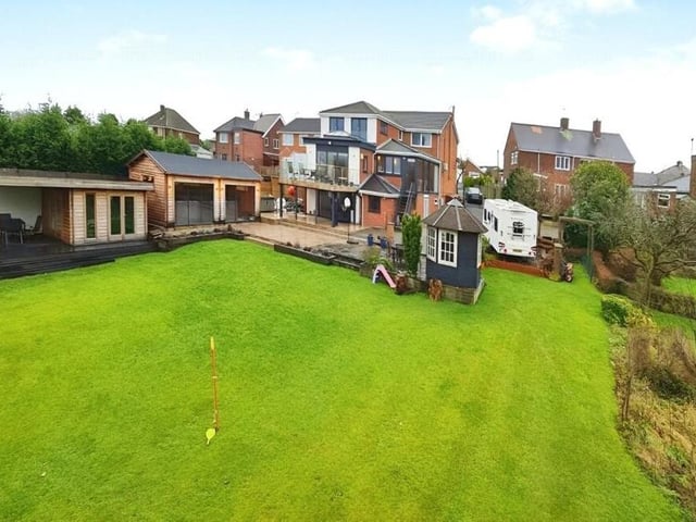 Let's switch our attentions to the exterior of the house now, and here is a view from the rear garden. You can make out the three floors, the balcony and all the outbuildings, which include a swim spa and summer house.