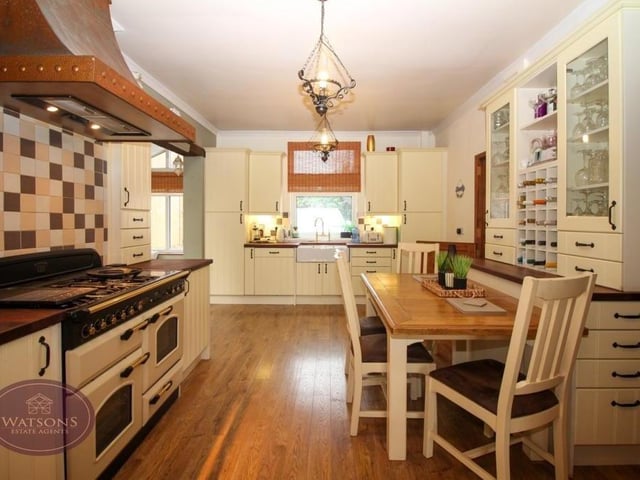 A second shot of the kitchen/diner, which includes a range of matching wall and base storage units, plus work surfaces incorporating an inset Belfast sink. Engineered wooden flooring and space for a breakfast table.