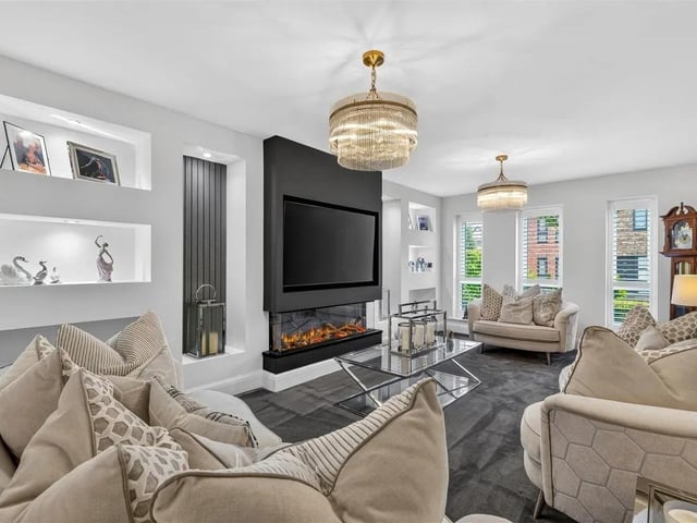 A beautifully appointed reception room with media wall with modern inset remote controlled log effect flame fire, underfloor heating and three floor-to-ceiling double glazed windows with fitted window shutters.