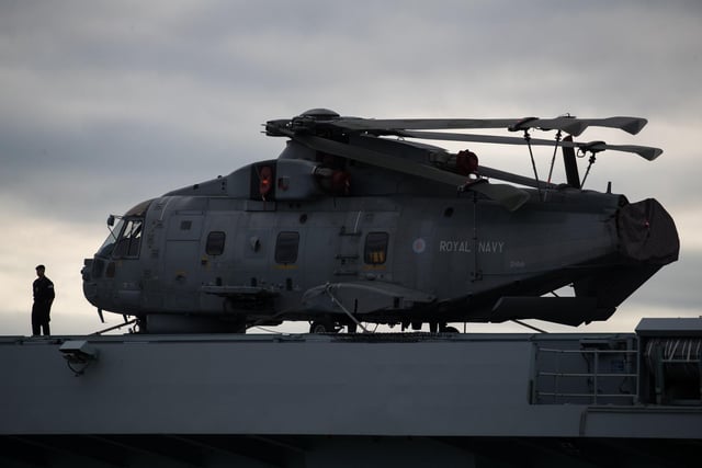A crew member stands next to a Merlin helicopter on the flight deck of HMS Queen Elizabeth as she leaves Portsmouth on September 9. Picture: Andrew Matthews/PA Wire