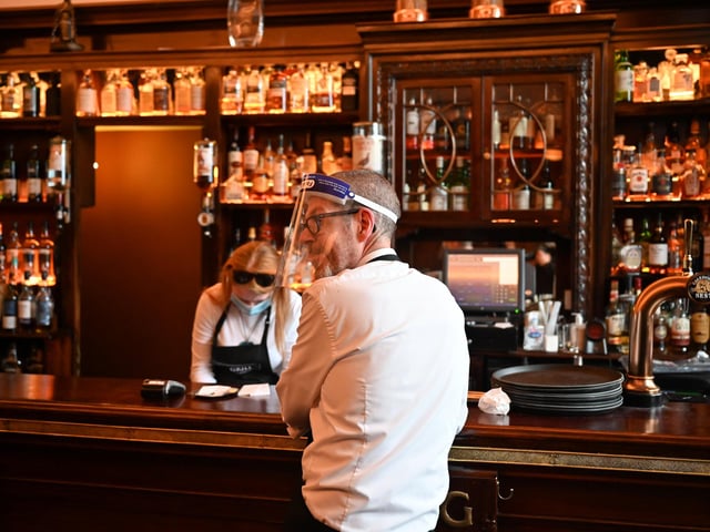 Kieth McKenzie wears a shielding face mask as he works in the pub The Grill and prepares to close. (Photo by Jeff J Mitchell/Getty Images)