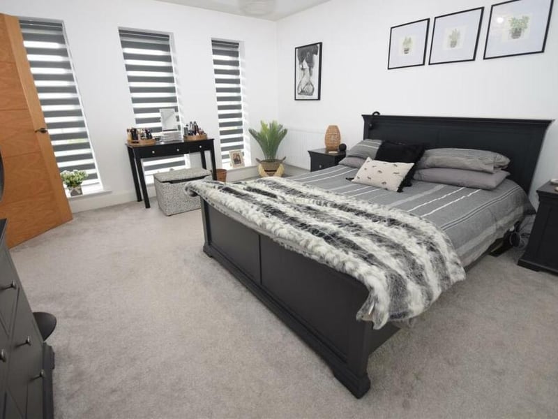 The second bedroom from a different angle, showing three windows overlooking the front of the house and offering plenty of natural brightness.