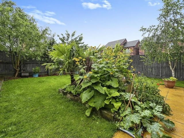 The enclosed garden at the back of the property includes a nice mix of turf and decking, with plants, shrubs and trees.