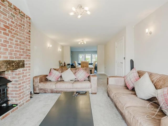 Inviting private reception room showcasing a feature log burner set within a charming brick surround, complemented by a bay front window and open access to the adjoining dining area.