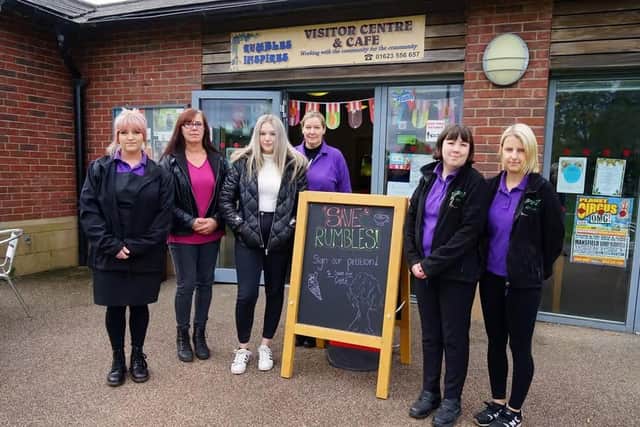Staff with 'Save Rumbles' sign at Rumbles Community Cafe.