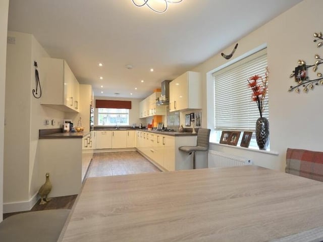 Next stop on our tour is the open-plan dining kitchen, which is a beautifully finished, triple aspect space, fitted with a range of high-gloss wall cupboards, base units and drawers with work surfaces over.