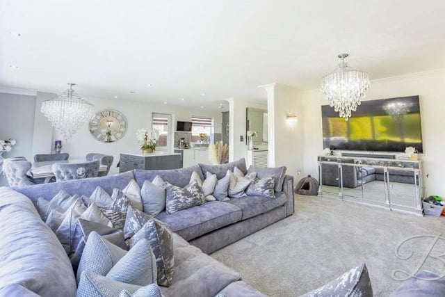 The open-plan living area oozes luxury. A carpeted floor and stylish wall-lights add to the feeling of warmth.
