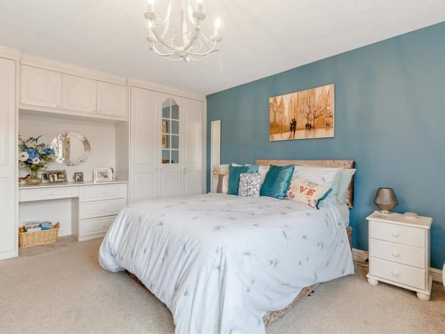 The master bedroom benefits from extensive fitted wardrobes to one wall, complete with hanging rails and shelving, overhead storage cupboards and a central dressing table.
