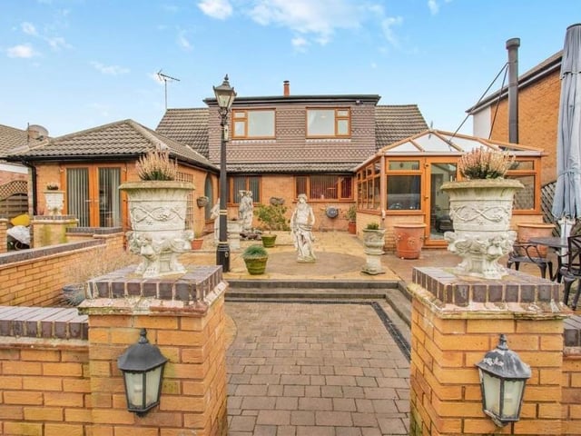 Here is a view of the property from the rear garden. Seating areas and several ornamental features add to the appeal of the outdoor space.