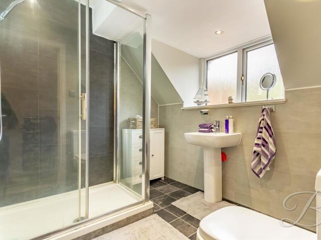 The first floor of the property also houses this family shower room. It comes complete with an enclosed shower, pedestal sink, low-flush WC and modern tiling.