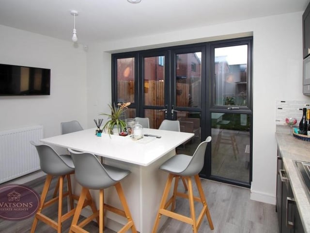 The kitchen also features a central island, offering further storage space and room for chairs, as well as French doors leading to the back garden. Ceiling spotlights and luxury vinyl tiled flooring add to the appeal of the room.
