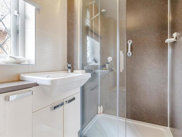 This en suite bathroom adds to the appeal of the master bedroom. A modern three-piece suite comprises a shower enclosure with sliding door, a vanity unit with inset wash hand basin and a low-flush WC. There are also a work surface, storage cupboards, tiled walls and a heated towel-rail.