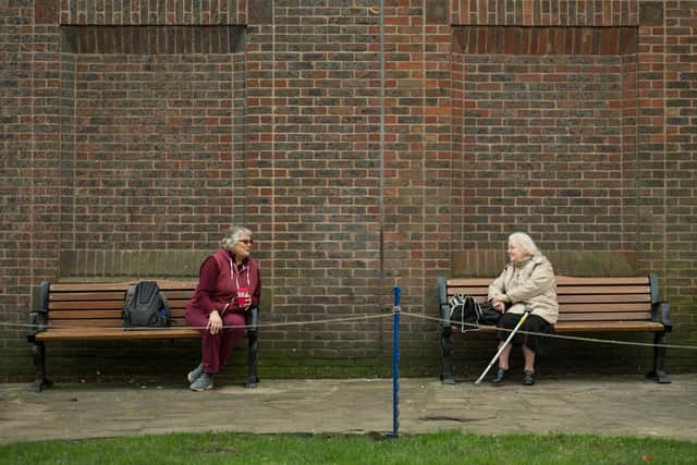 Two women observe social distancing measures as they speak to each other from adjacent park benches amidst the novel coronavirus COVID-19 pandemic, (Photo by OLI SCARFF/AFP via Getty Images)
