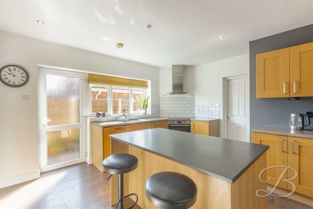 Other features of the kitchen include a stainless steel inset sink with mixer tap above, a ceramic hob with extractor fan, downlights and a window and door facing the side of the bungalow.