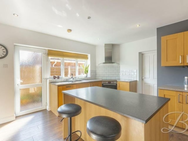 Other features of the kitchen include a stainless steel inset sink with mixer tap above, a ceramic hob with extractor fan, downlights and a window and door facing the side of the bungalow.