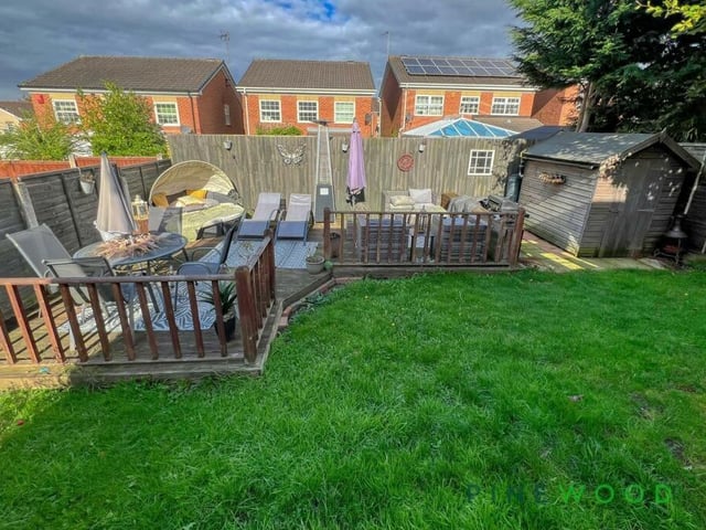 Here is an elevated view of the back garden, showing extensive decking area, lawn and handy shed.