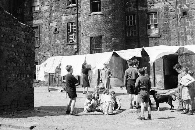 Glasgow - Typical back court scene in old property - children playing and a woman hanging out the washing.