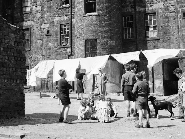Glasgow - Typical back court scene in old property - children playing and a woman hanging out the washing.