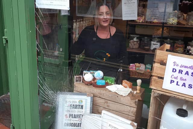 Tara Copper looking at the smashed window from inside the Mother Earth shop on Toothill Lane