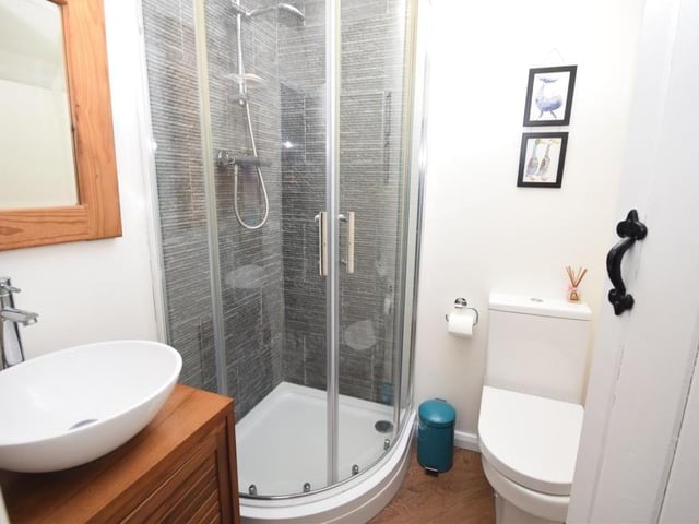 This is the en suite shower room to the second of the upstairs bedrooms. It features a shower cubicle, low-flush WC and modern wash hand basin with mixer tap, set in a vanity cabinet. The room is bright, thanks to a large Velux rooflight.