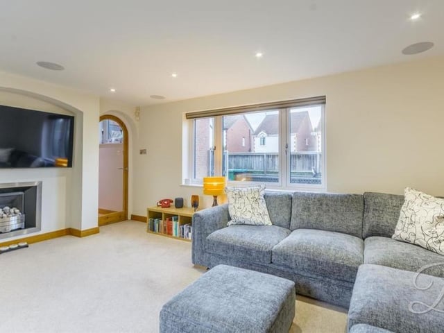 The bright lounge or living room from a different angle. As well as the French doors, a triple-glazed window facing the front of the property ensures lots of natural light. Note also the carpeted floor and feature fireplace.