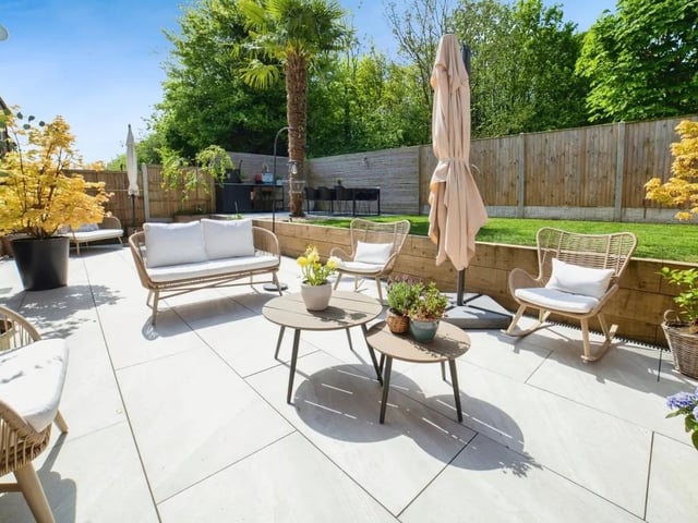 The rear garden is split into levels with large patio and barbeque area, dining area and grass.