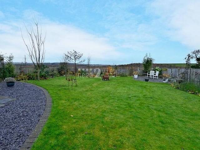 Much of the rear garden is laid to lawn. It is well maintained, featuring planted borders, and is enclosed by fencing.