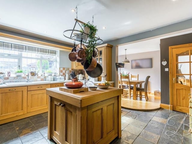 The dining room (see background) flows seamlessly into the stylish and sizeable kitchen, which is fitted with shaker-style wall and base units and features an eyecatching central island.