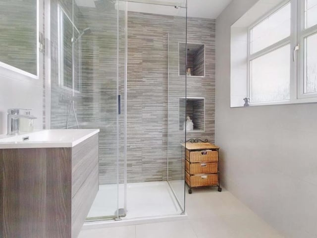 The modern en suite to the main bedroom features a walk-in shower and a vanity sink.