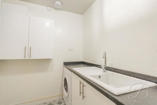 Across the hallway from the kitchen is this useful utility room.  It has an inset sink and drainer, storage cupboard, worktop and also space for a washing machine and tumble dryer