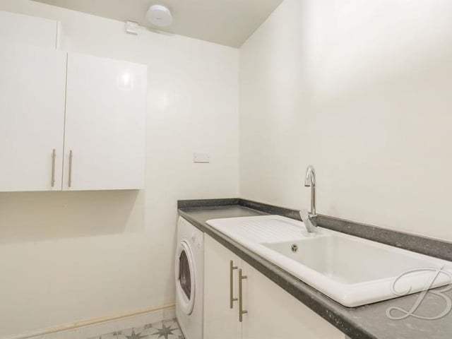 Across the hallway from the kitchen is this useful utility room.  It has an inset sink and drainer, storage cupboard, worktop and also space for a washing machine and tumble dryer