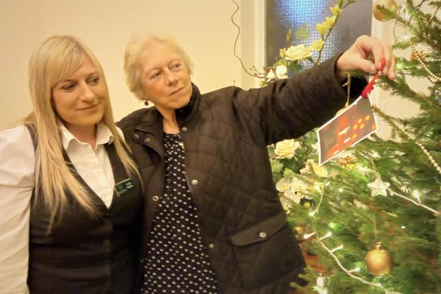 Funeral director Jodie Wardle hangs a label dedicated to her dad, John, alongside her mum Jenny to launch Gillotts Funeral Directors’ Christmas remembrance appeal at its Kimberley branch.