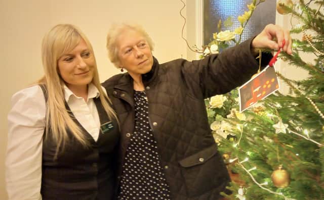 Funeral director Jodie Wardle hangs a label dedicated to her dad, John, alongside her mum Jenny to launch Gillotts Funeral Directors’ Christmas remembrance appeal at its Kimberley branch.