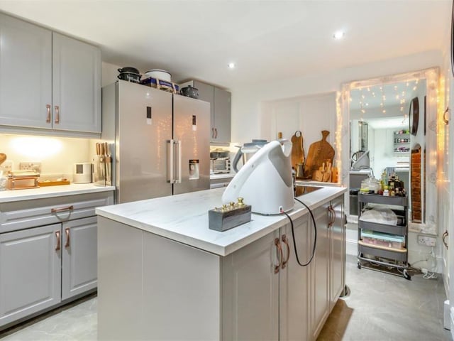 The kitchen comes in two parts, with the main area containing shaker-style wall cupboards with under-lighting, base units and marble-effect worktops. The floor is laminated, and there is space for a fridge/freezer.