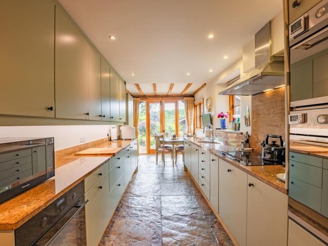 Moving on now to the lengthy, narrow and sleek breakfast kitchen. At one end is space for a small dining or breakfast table, in front of another set of double French doors that flow naturally into the garden