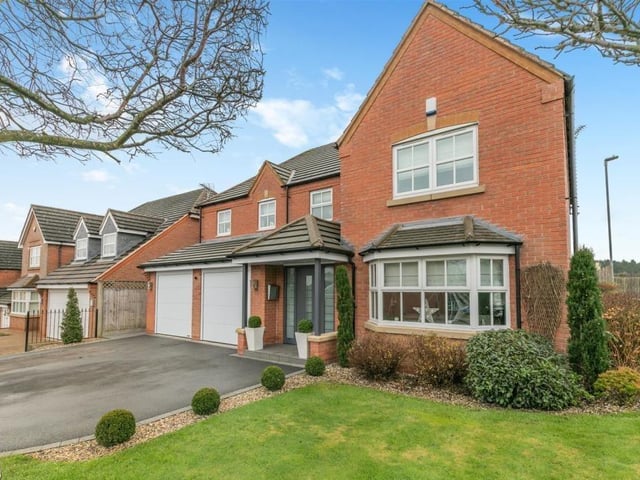 Back to the front of the house for a photo that shows a wide tarmac driveway, giving off-street parking space for up to three cars. It also leads to an integral double garage, equipped with power and light, plus remote-controlled, electric doors. Note also the attractive, open-fronted storm porch that protects a contemporary aluminium front door.