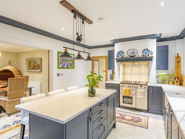 The kitchen features a free-standing range cooker with five-ring hob and extractor fan above, plus an integrated dishwasher and two integrated fridges.