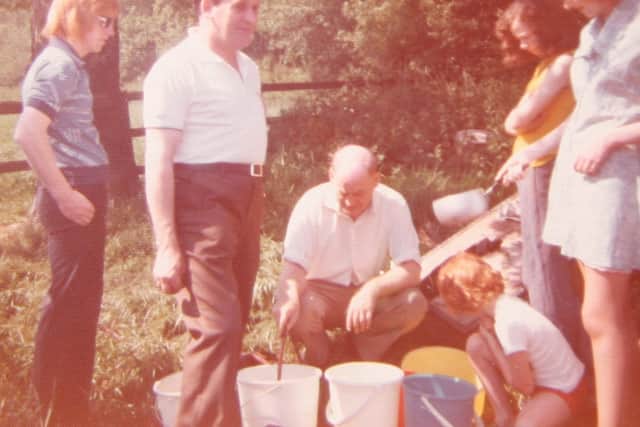 Residents collect water from a field tap meant for cattle during the summer of 1976.