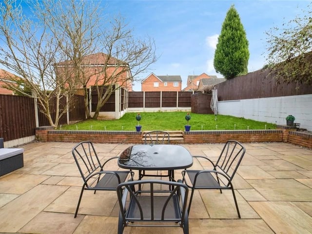 The garden is a private oasis that exudes modern elegance while remaining clean and tidy. A thoughtfully designed slabbed patio area offers a space for outdoor dining or relaxation. Seamlessly transitioning to a separate, well-maintained grass area, perfect for leisure or play.