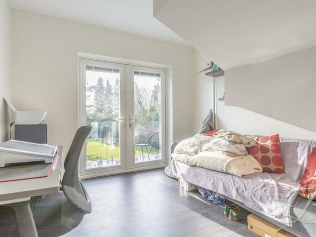 A potential fourth bedroom on the first floor has been turned into a home office with French doors leading to a balcony with glass balustrade that overlooks the back lawn.