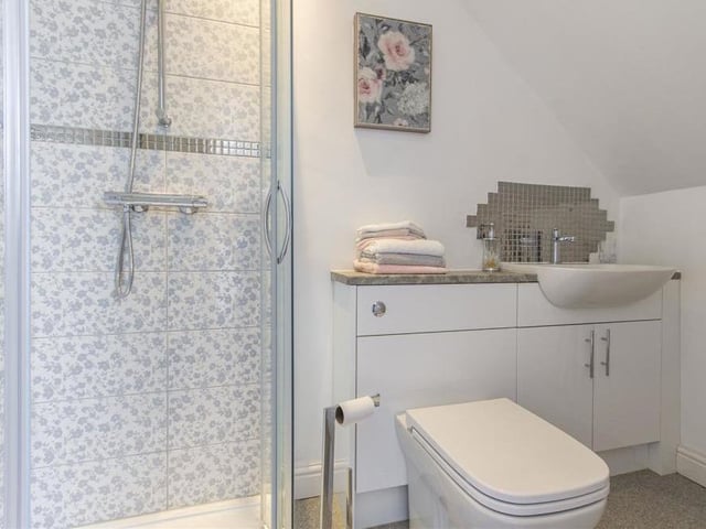 The first floor of the dormer bungalow on The Hill also includes this en suite shower room. It is fitted with a white, three-piece suite that comprises a corner shower cubicle, semi-inset wash hand basin with storage below, and a WC with concealed cistern. There's also a chrome, heated towel-rail.